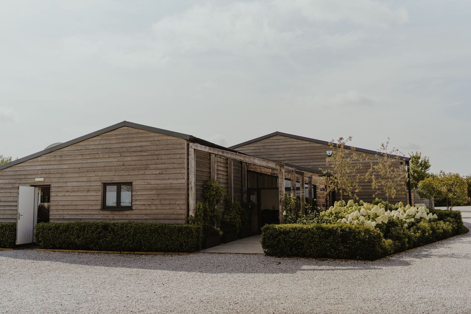 Modern wooden lodge buildings set against cloudy sky in rural setting.