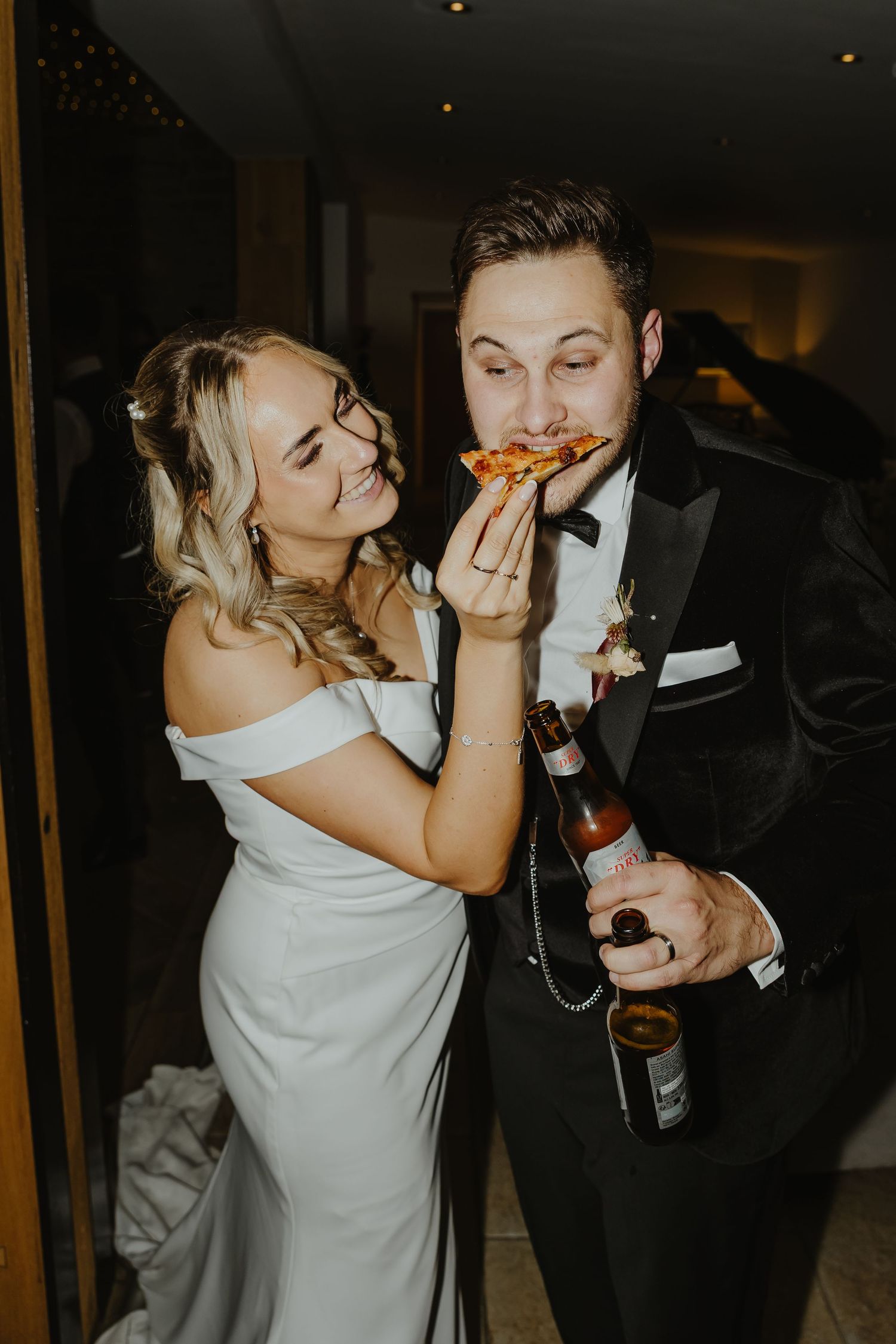 Wedding couple shares Pizza during romantic evening reception celebration.