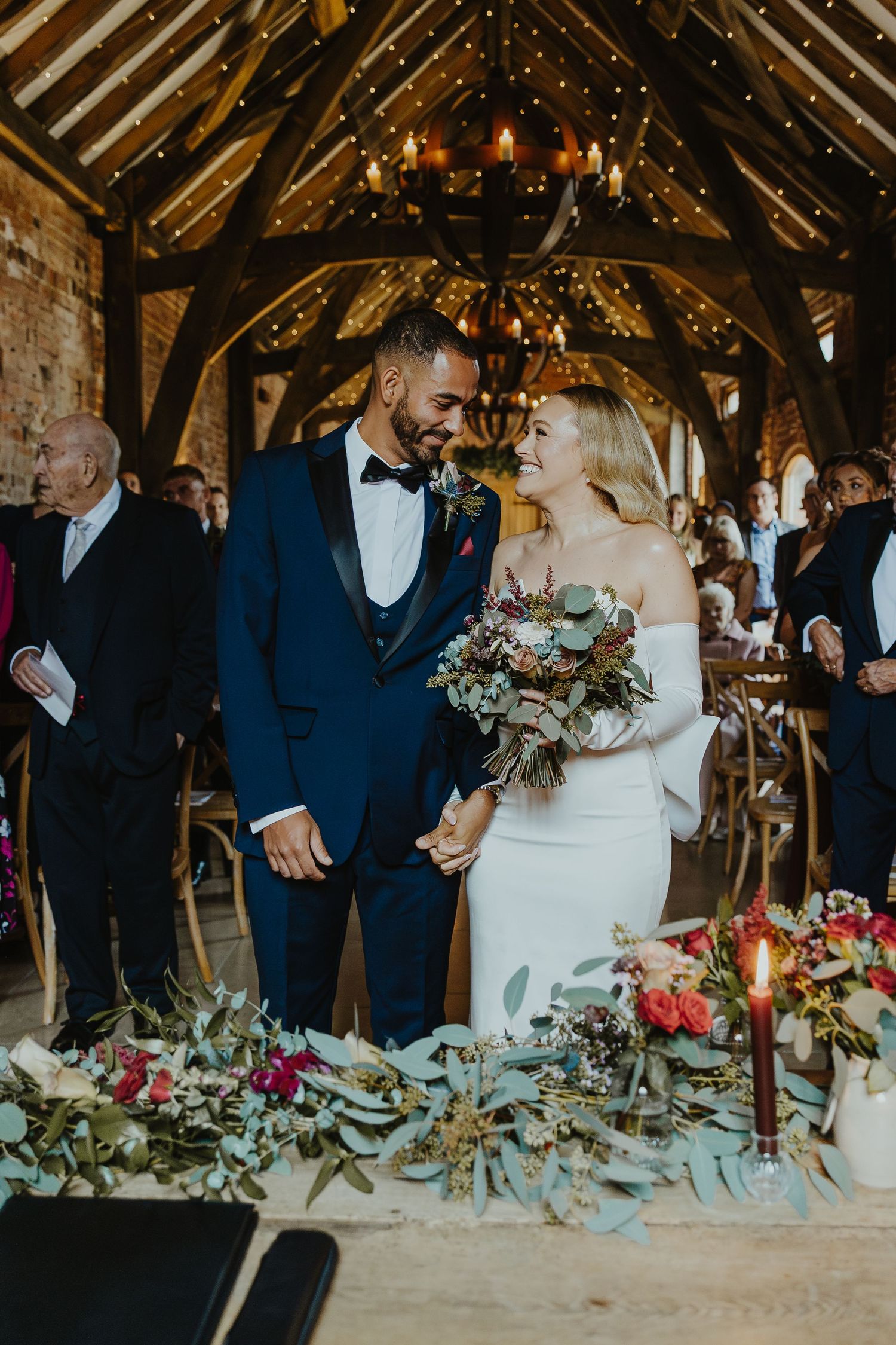 Rustic barn reception with twinkling lights and floral table decorations.