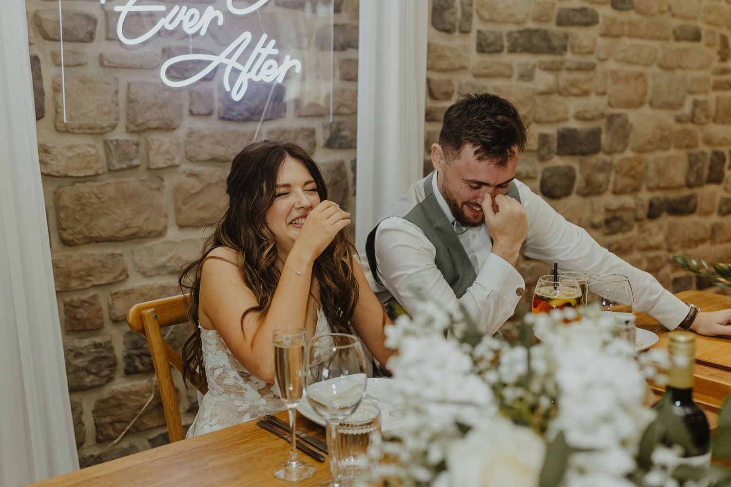 Wedding guests share an emotional moment at a rustic stone-walled reception venue.