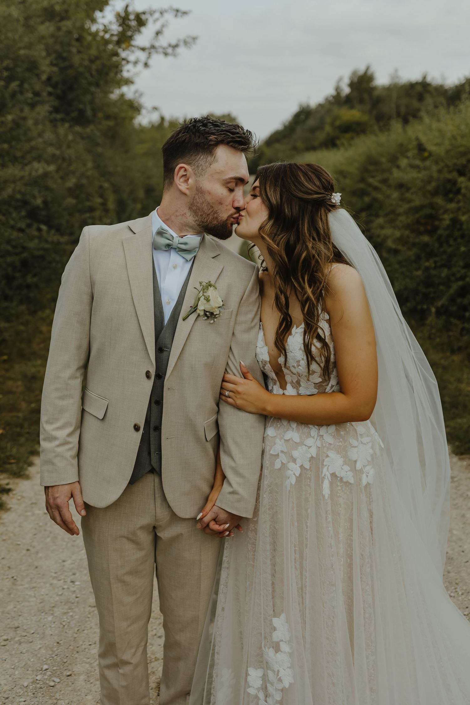 A romantic wedding portrait on a country path with the couple in elegant attire.