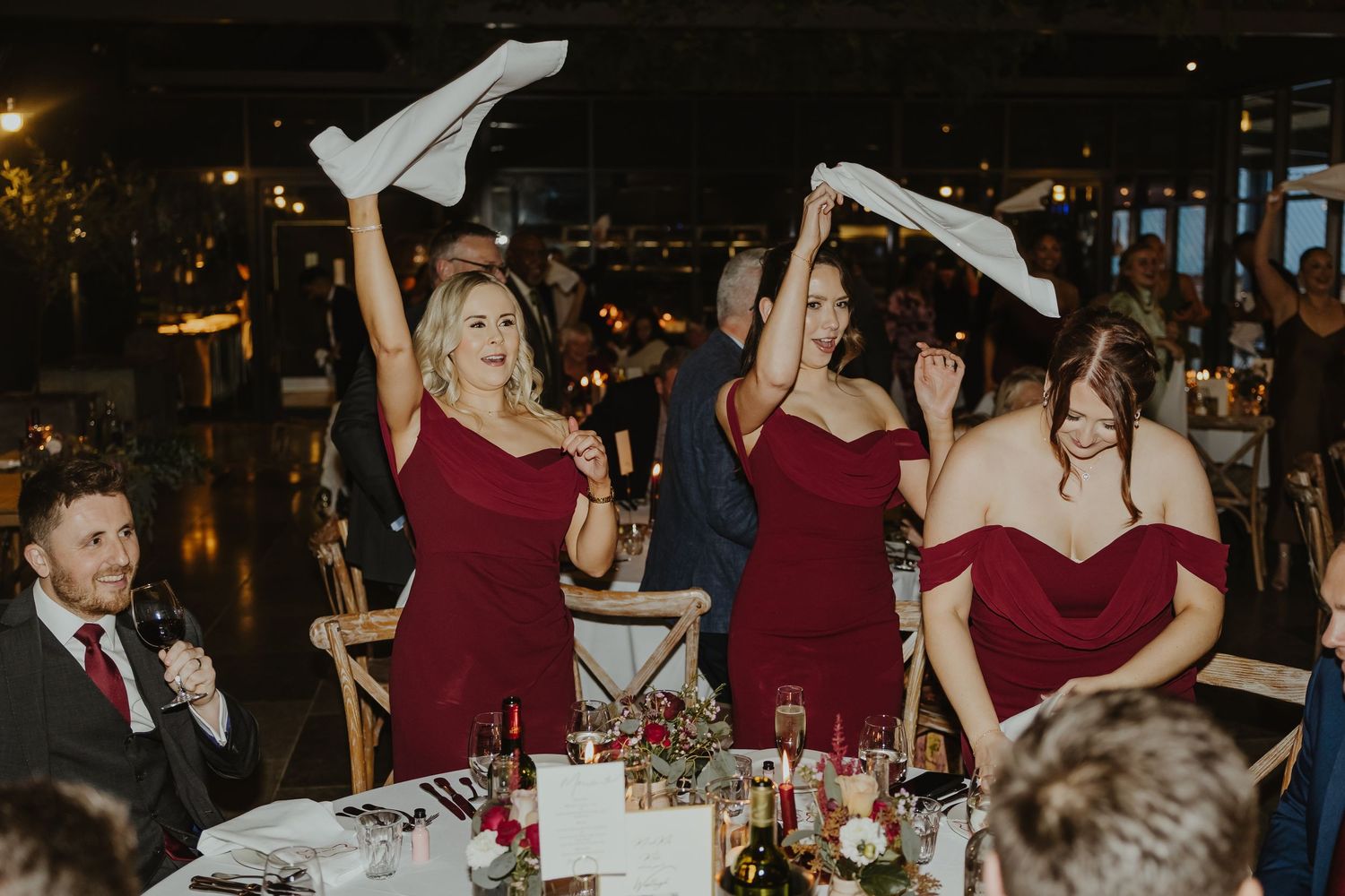 Wedding reception scene with guests waving napkins in celebration.