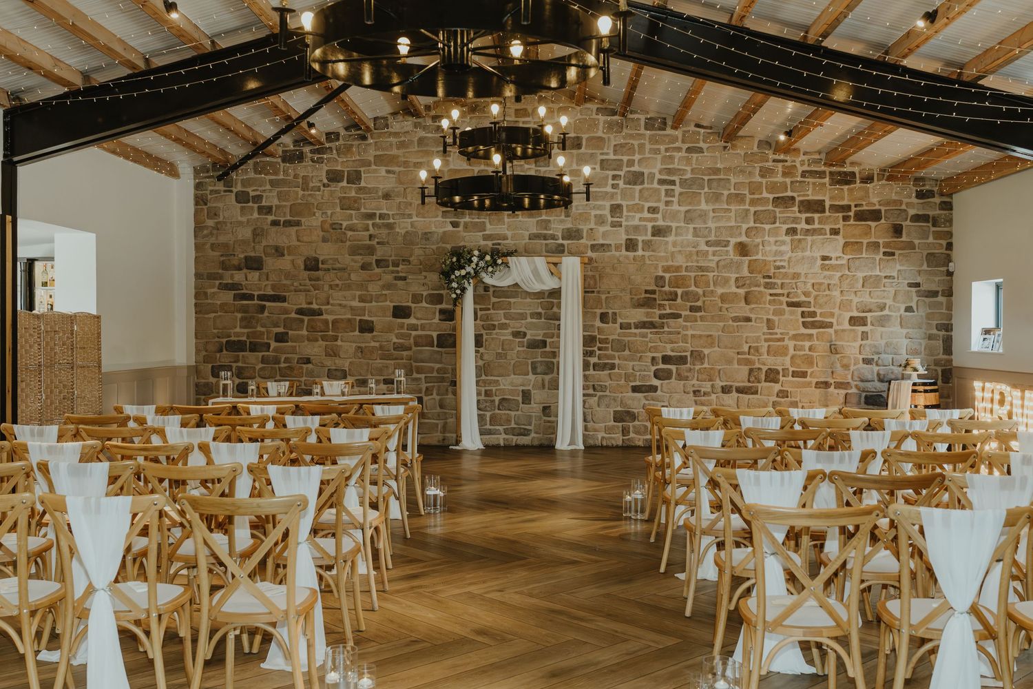 Rustic wedding venue interior with exposed brick walls and wooden beams ready for ceremony.