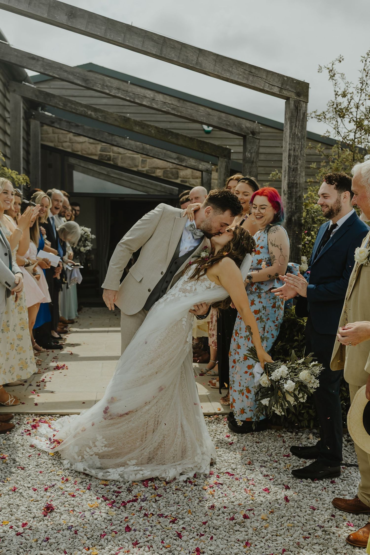 Wedding couple dips during first dance surrounded by guests throwing confetti on outdoor patio.