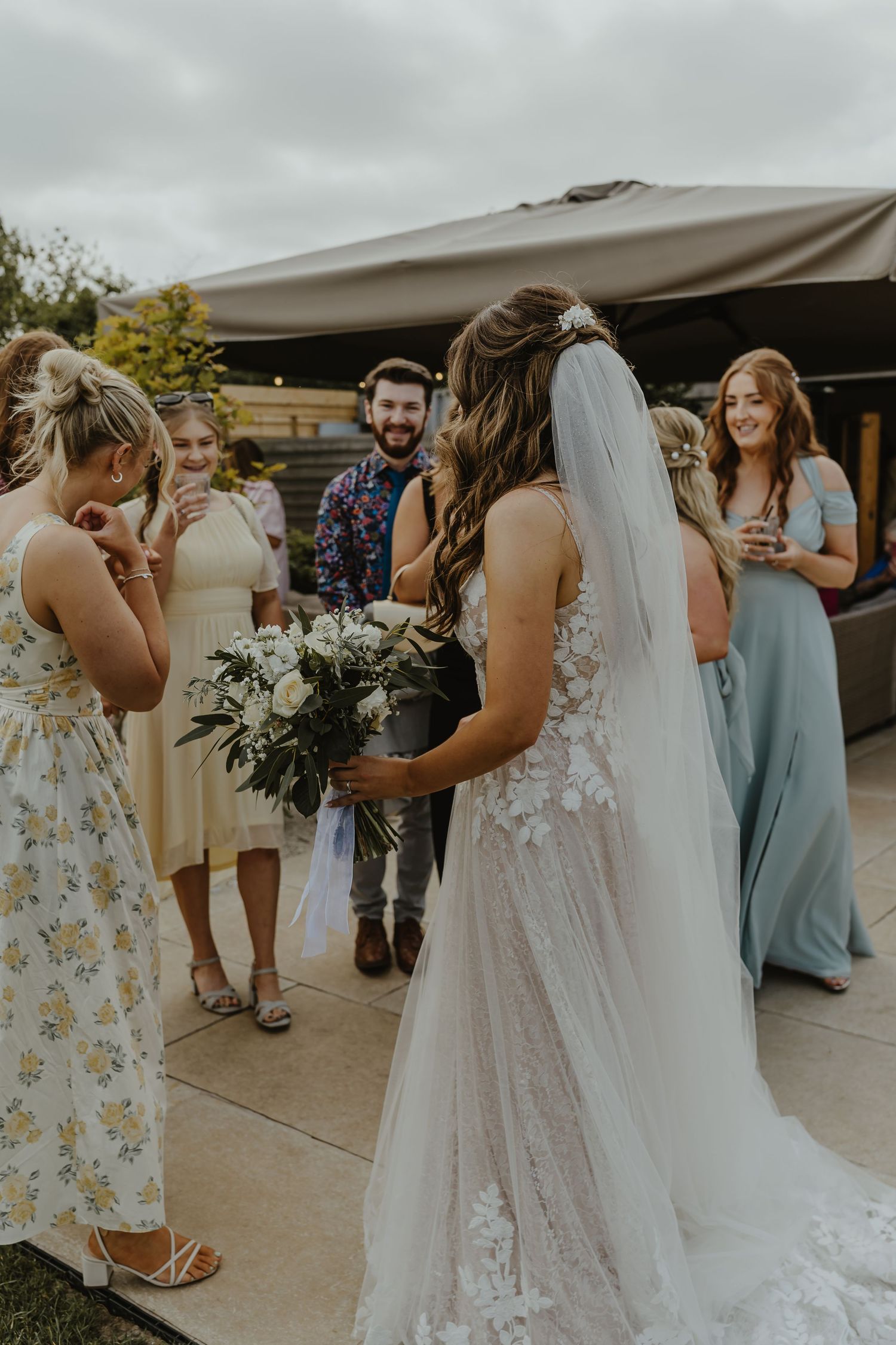 Wedding party gathers on patio during outdoor reception celebration.