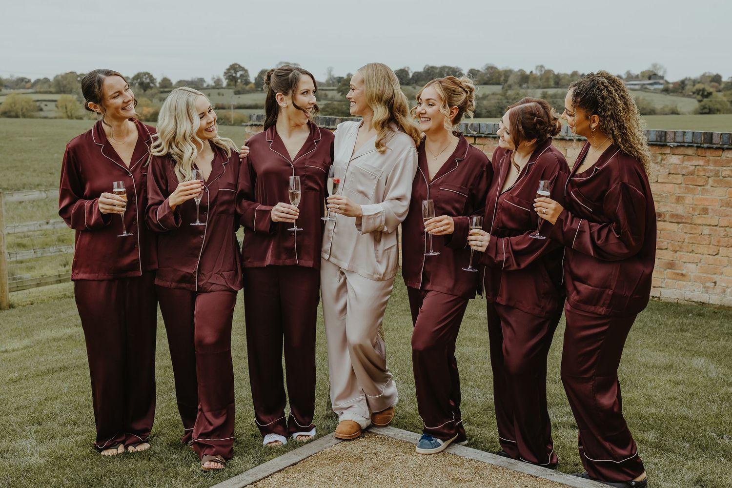 Wedding party in burgundy robes posing together outdoors.