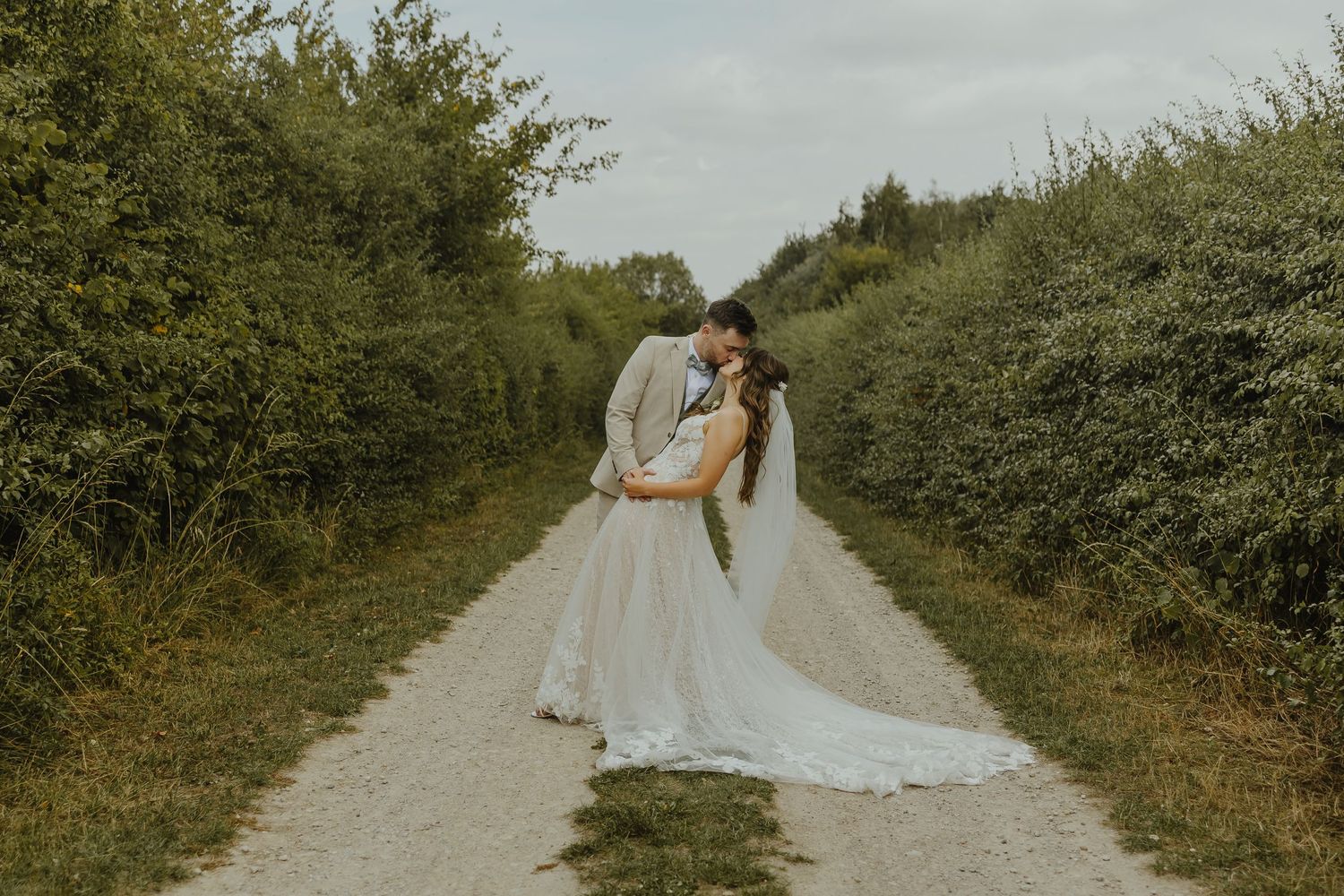 Wedding couple and bridal party walking down a tree-lined country path.