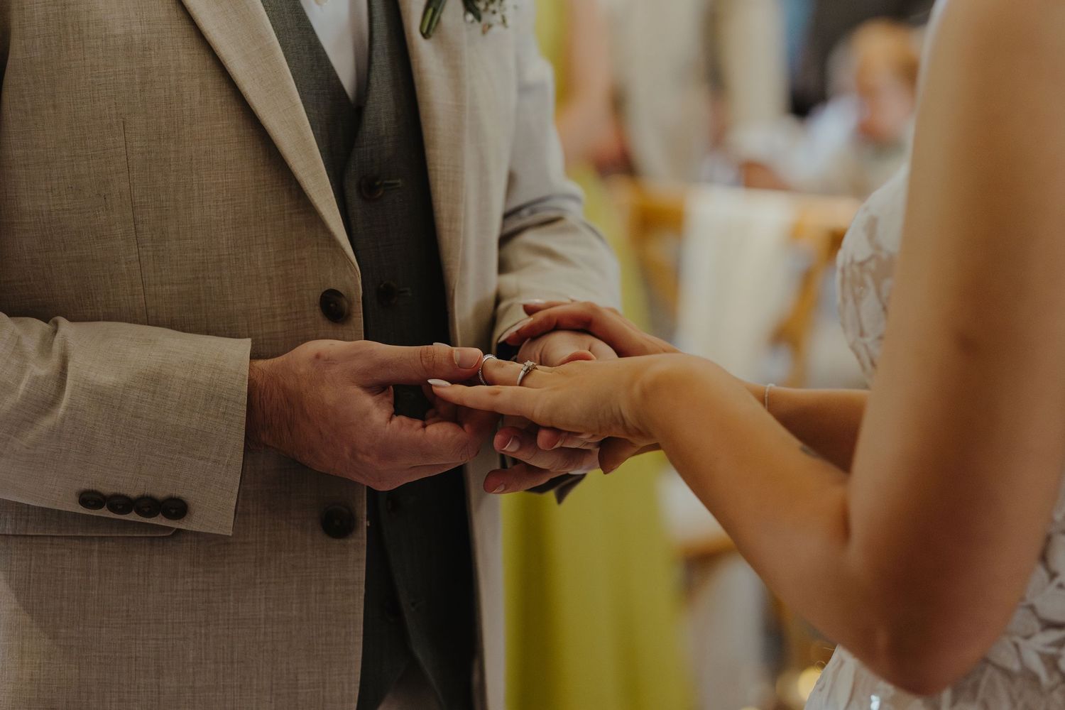 Close-up shot of hands exchanging wedding rings during a marriage ceremony.