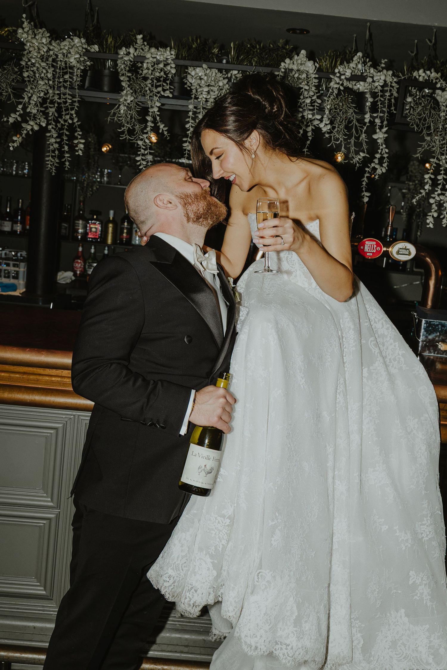 A sequence of wedding photos showing a couple sharing champagne and intimate moments under decorative white floral arrangements.