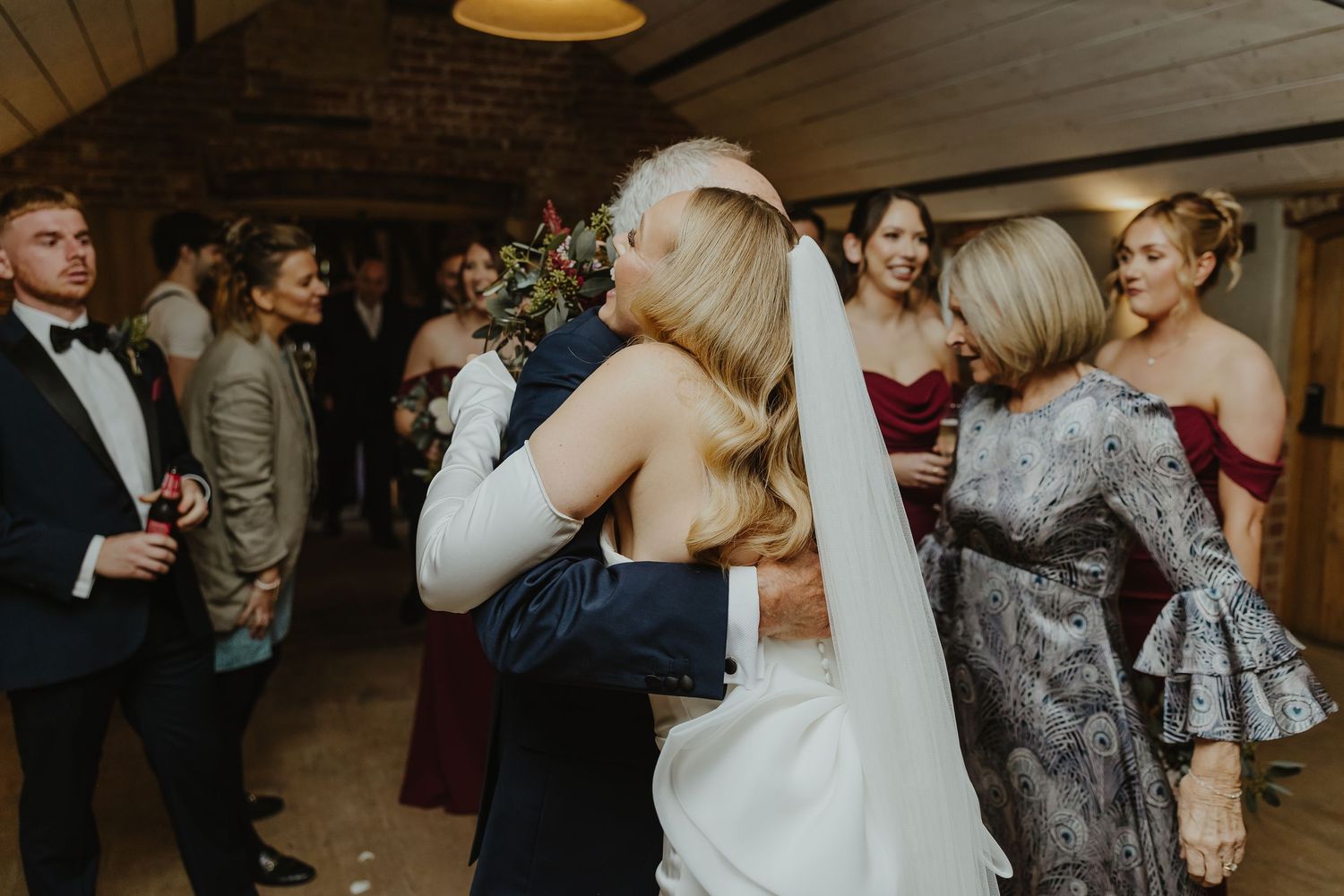 Wedding reception celebration in dimly lit rustic venue with guests watching first dance.