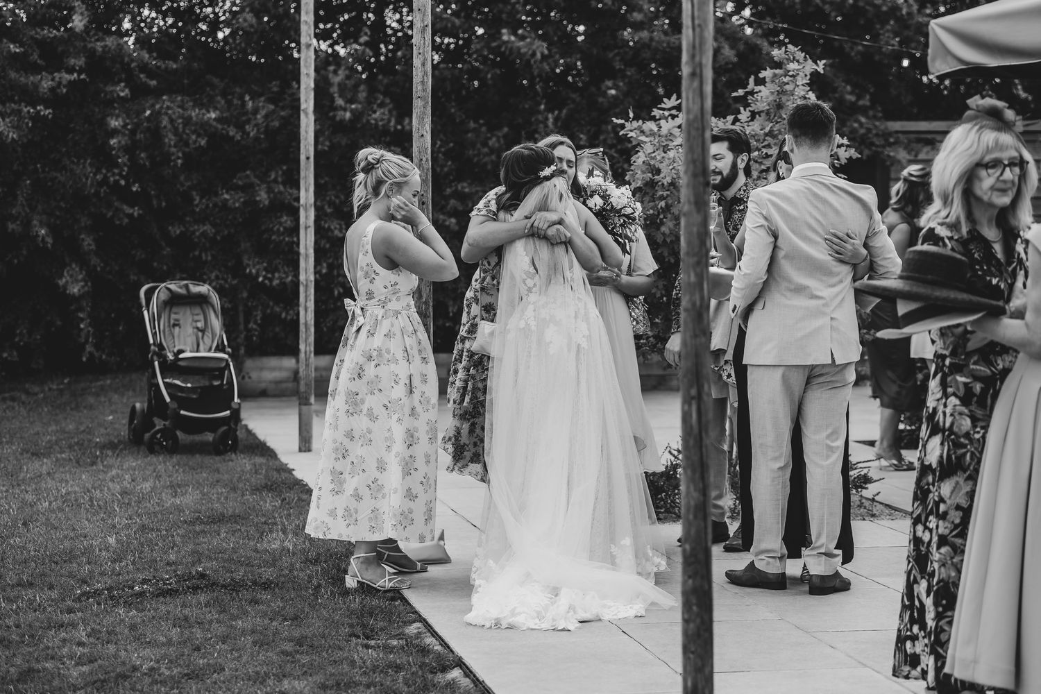 Wedding guests mingle during an outdoor reception with string lights and tents.