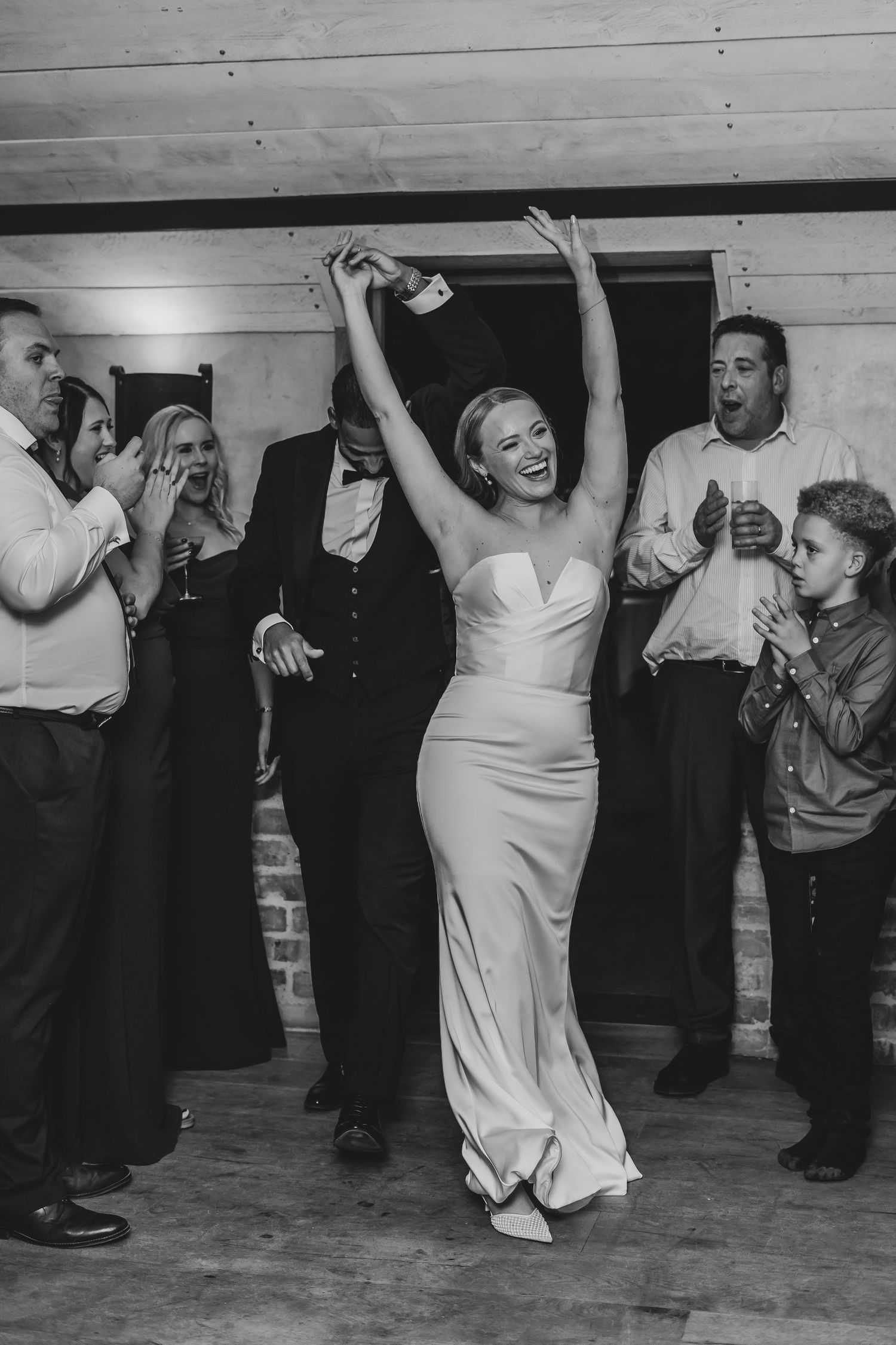 Black and white photo of wedding guests dancing at a reception.