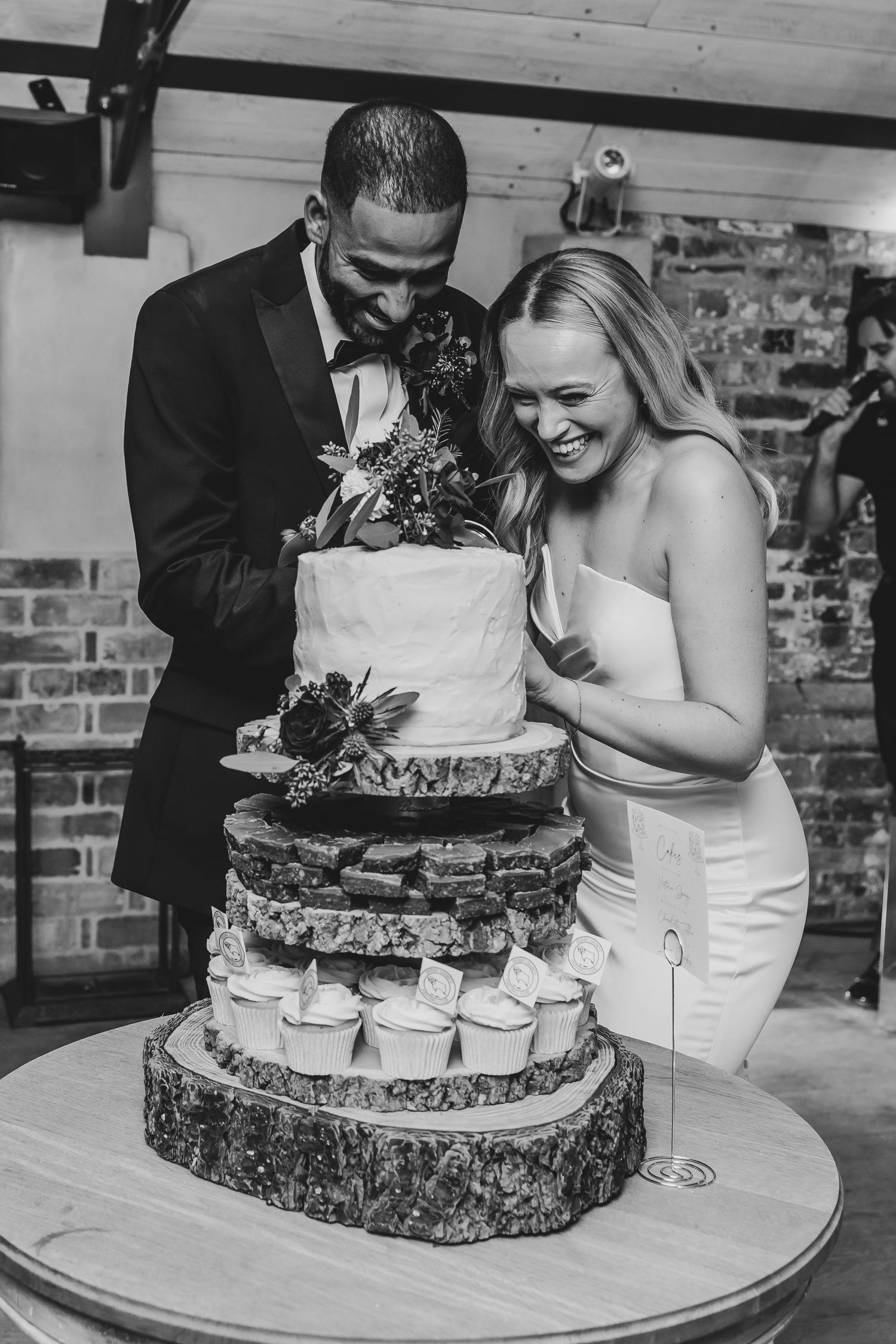 Wedding cake cutting moment captured in black and white photography.