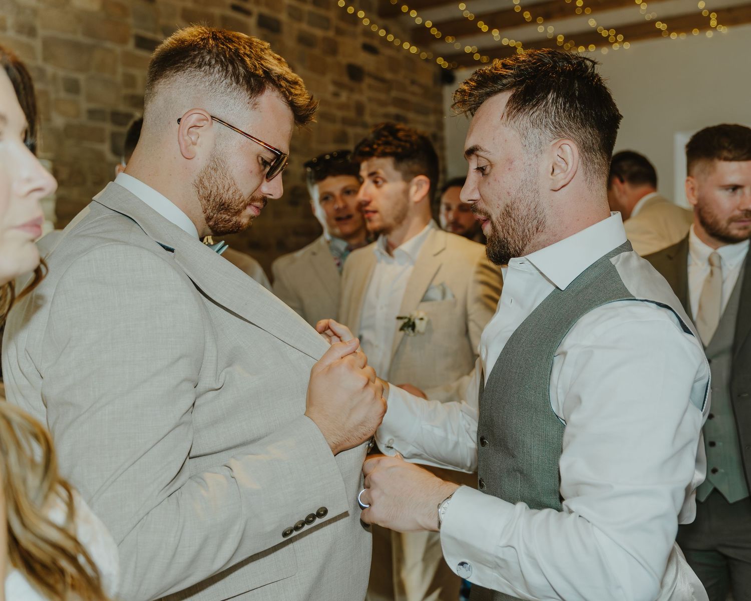 Wedding party members in gray suits sharing celebratory drinks and embraces.