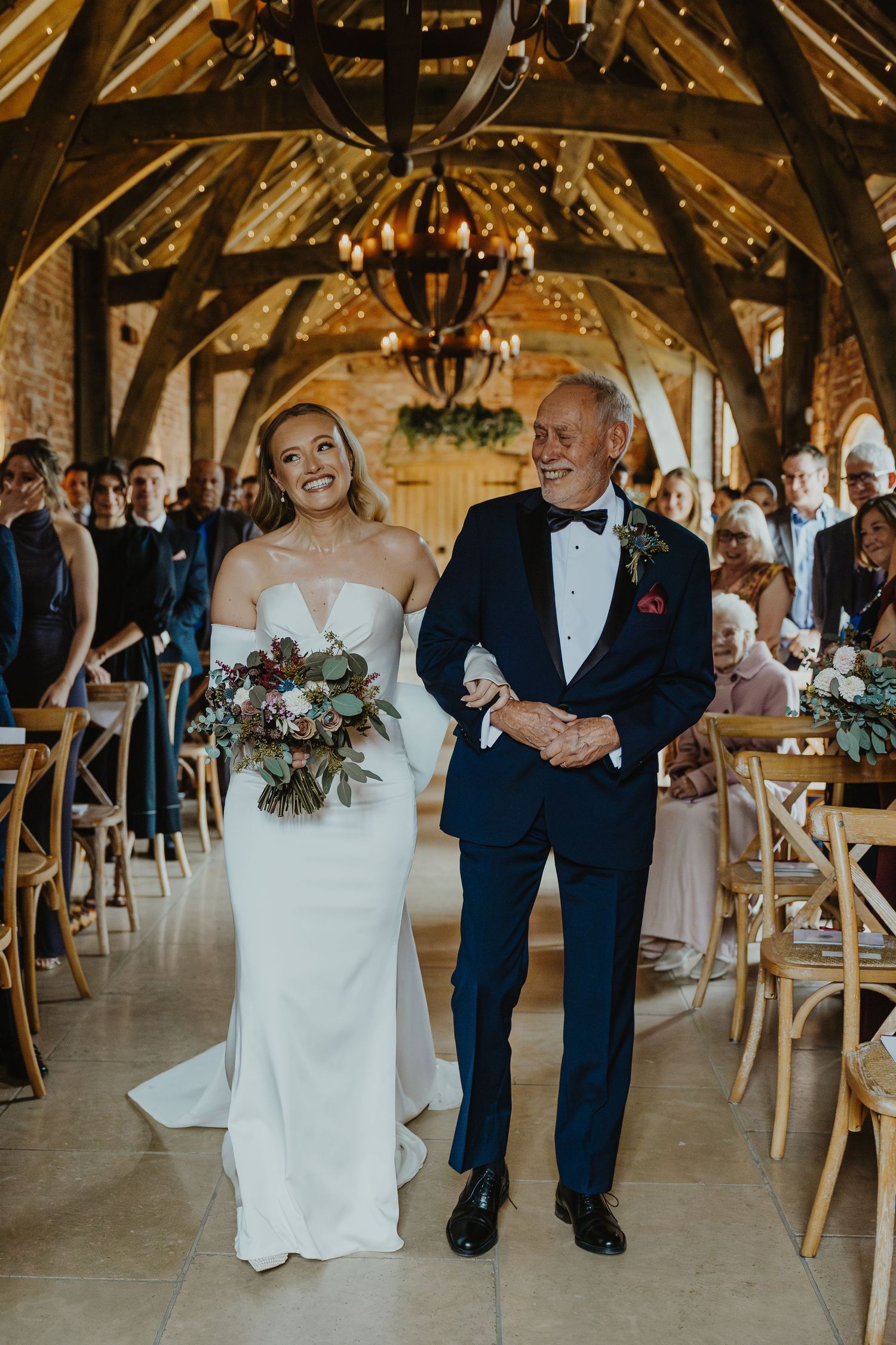 Rustic barn wedding reception with wooden beams and warm lighting during celebratory dance.