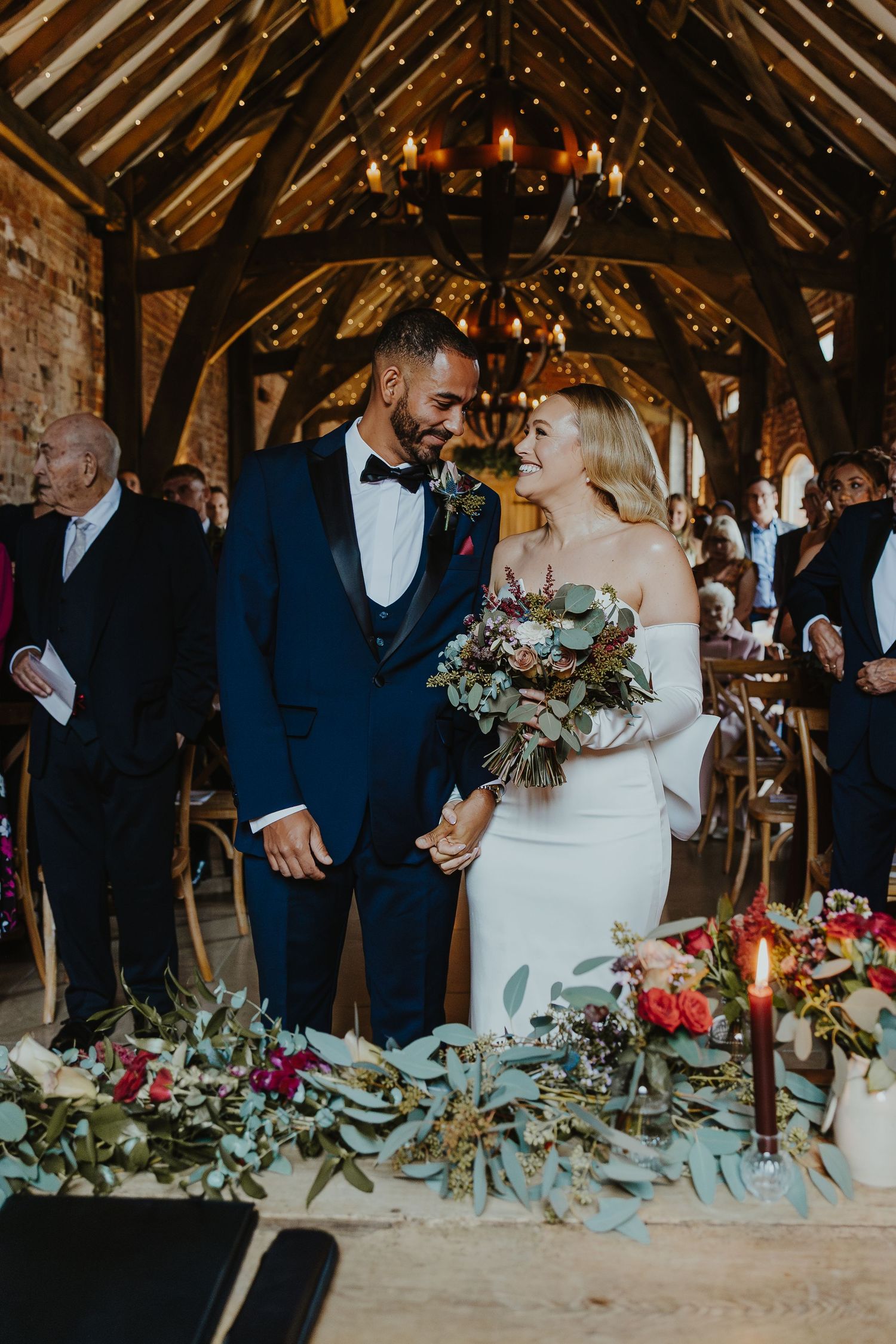 Rustic barn wedding reception with elegant floral table decorations and candlelight.