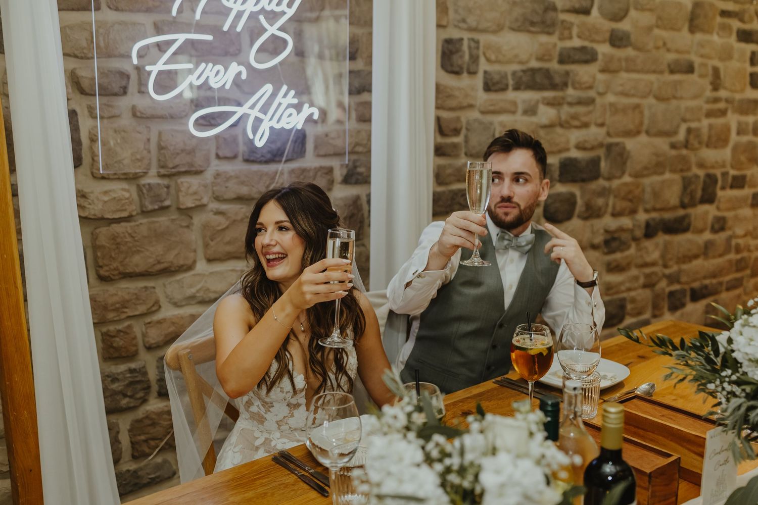 Wedding reception setup featuring rustic decor and stone wall backdrop.