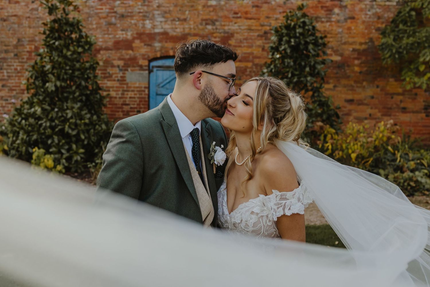 Romantic moments captured against brick wall backdrop during wedding photoshoot.