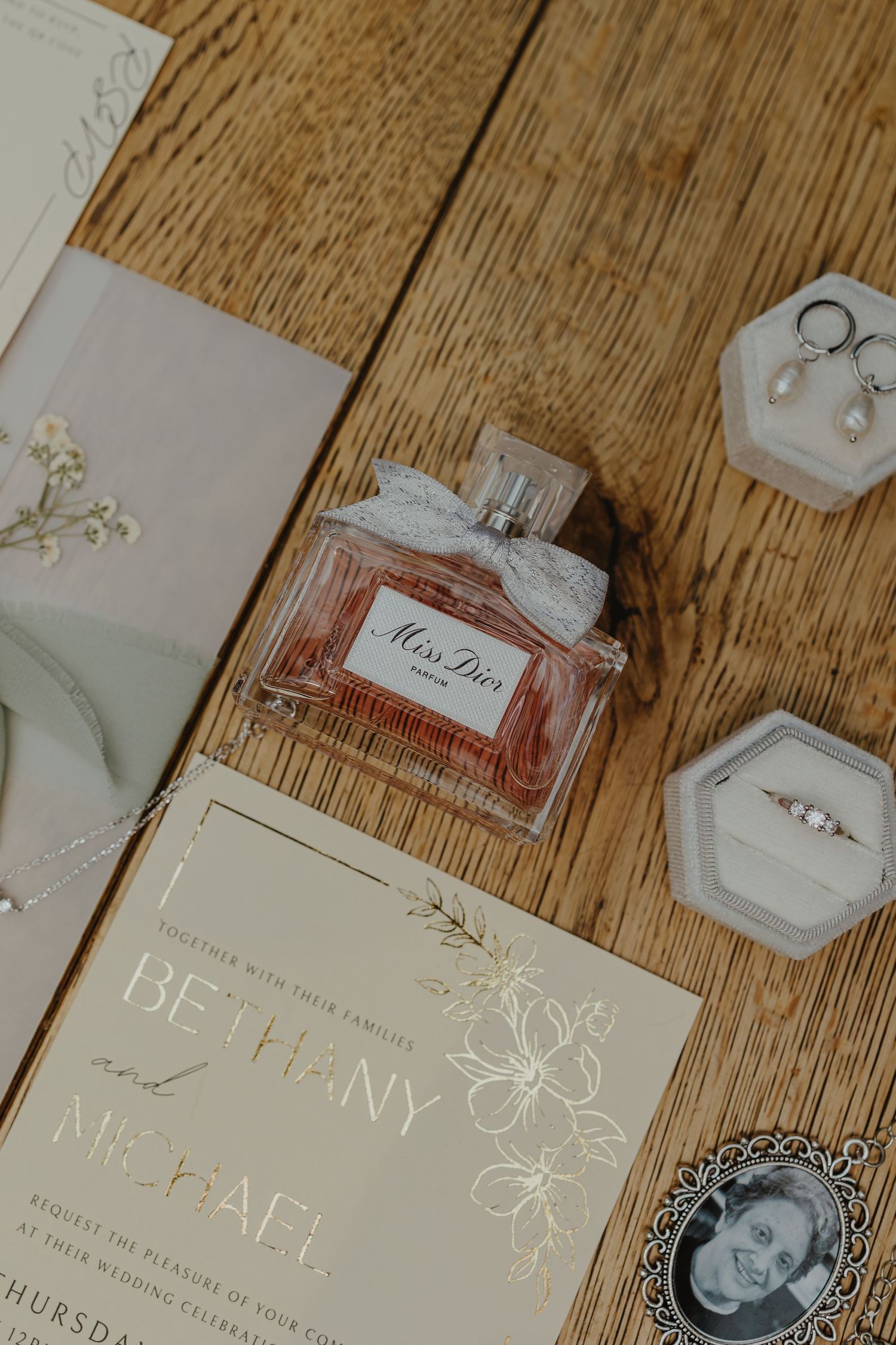 Elegant wedding invitations with floral details laid out on wooden surface.