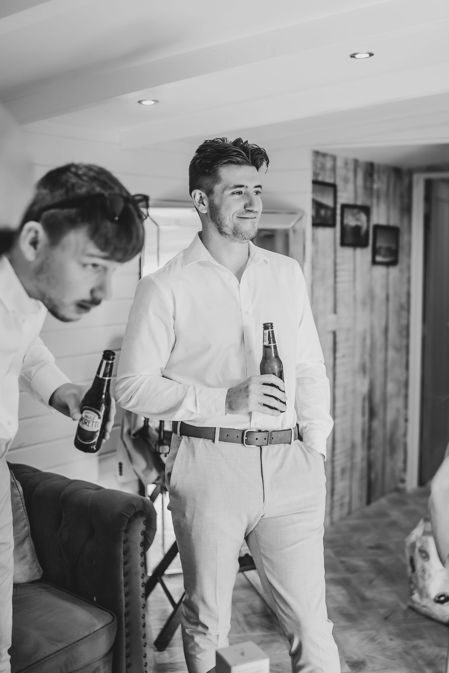 Group in white shirts and khakis holding drinks in rustic indoor setting.
