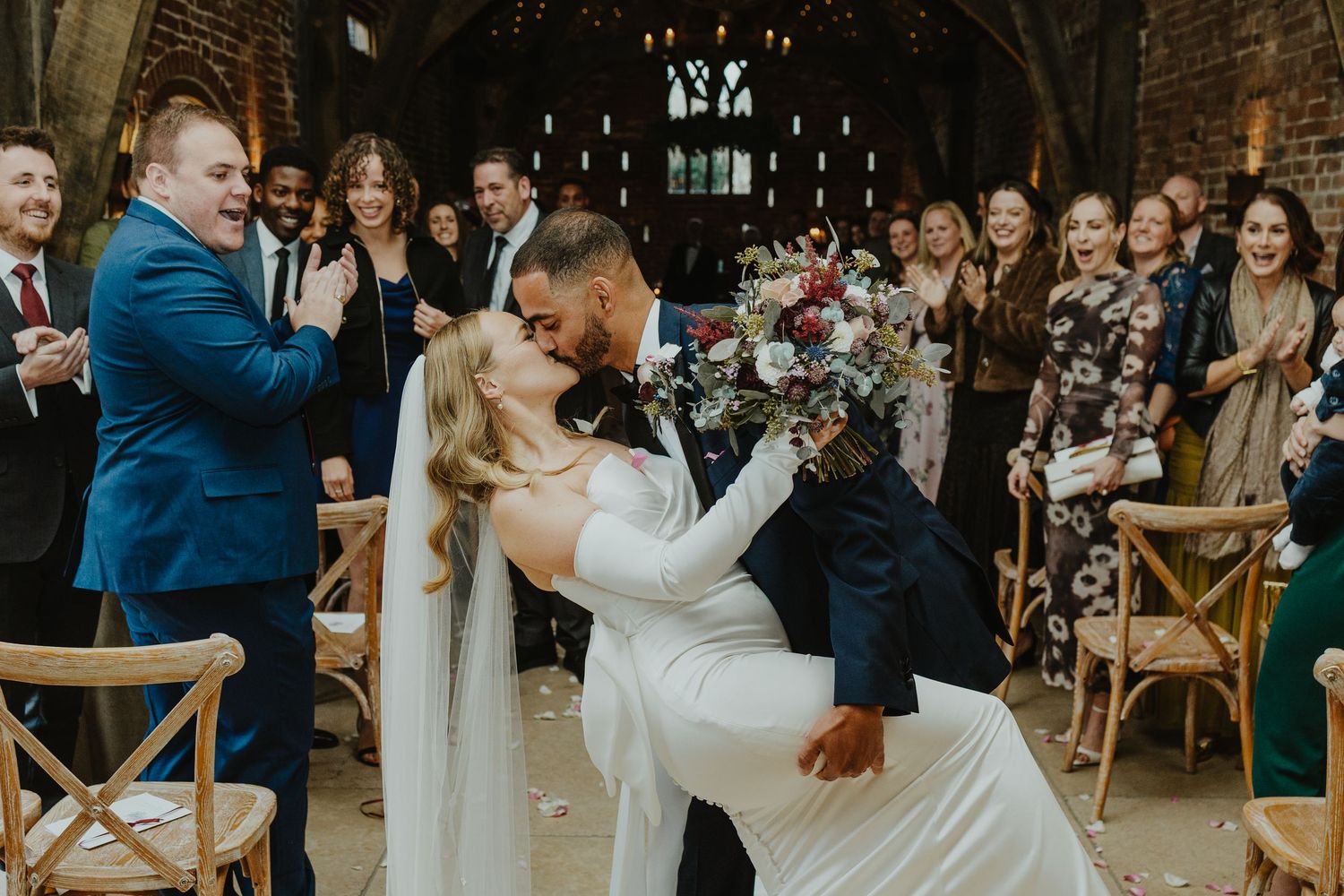 Wedding reception scene in rustic barn venue with exposed wooden beams and elegant decor.