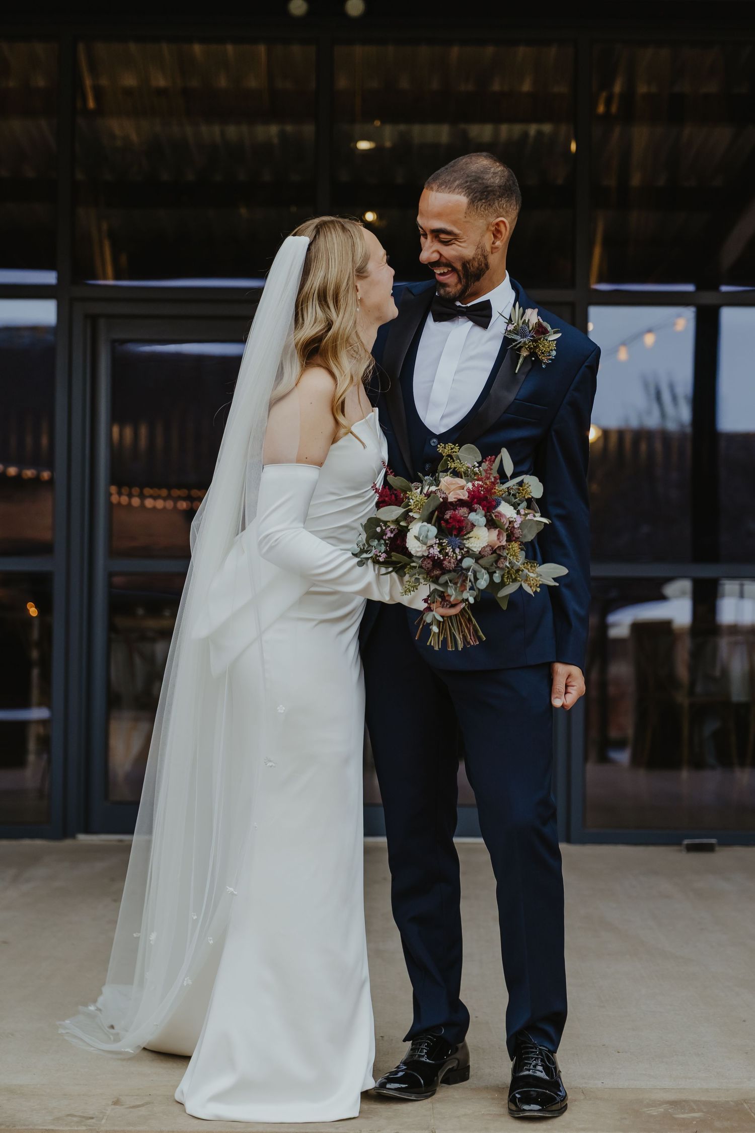 Couple shares intimate moment during outdoor wedding portraits at rustic venue.
