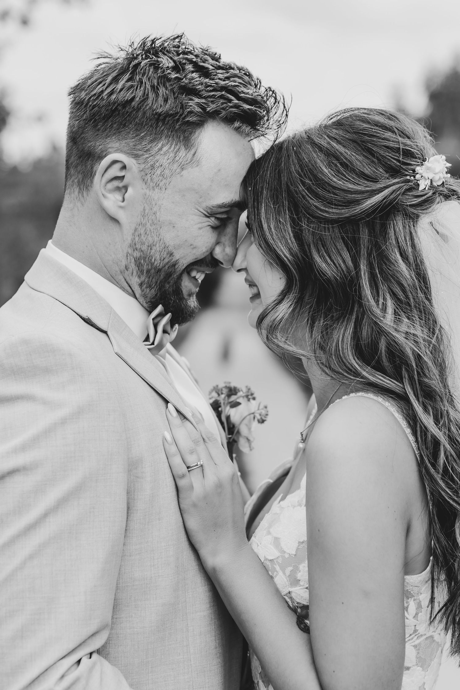 A black and white portrait of a wedding couple sharing a romantic moment.