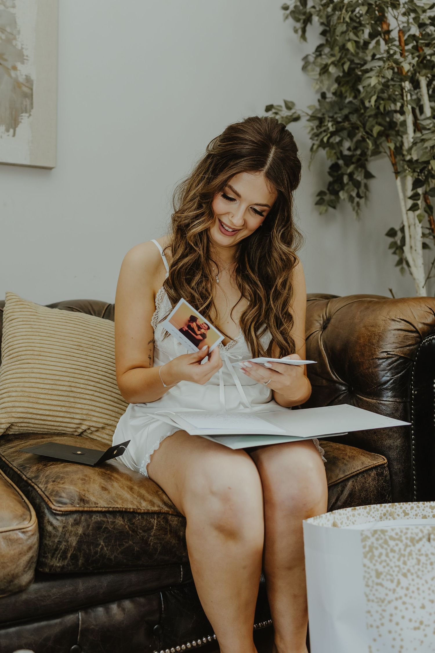 Someone in white dress sitting on couch writing in natural light.