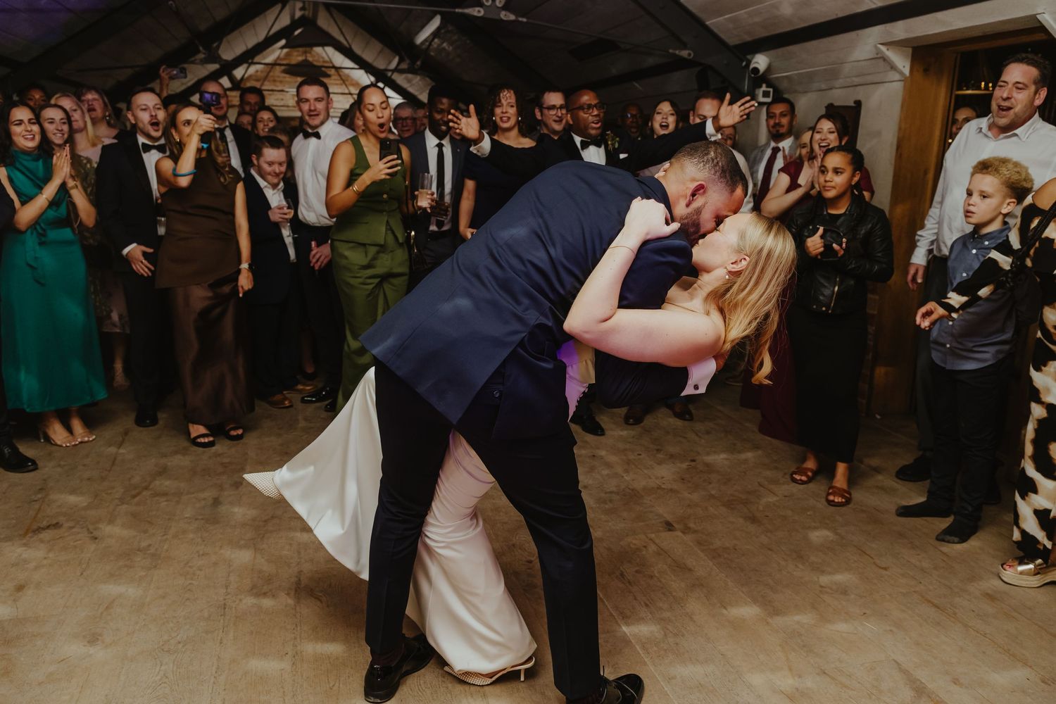 A couple performs a dramatic dip during their wedding dance as guests watch.