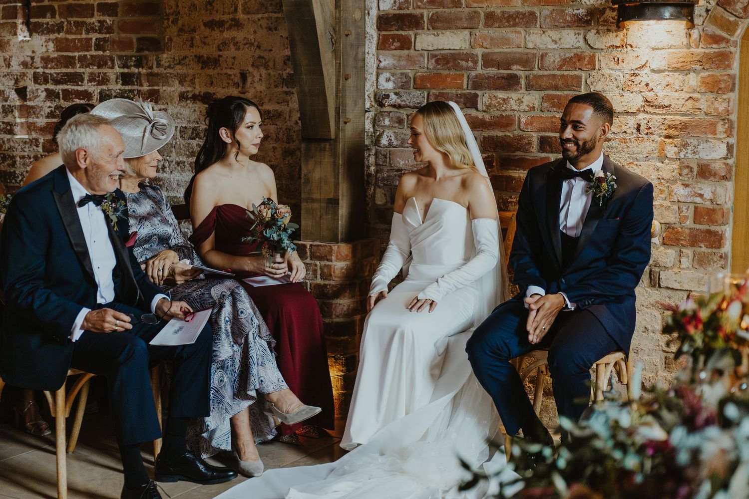 Wedding ceremony in a rustic brick venue with floral decorations and natural light.