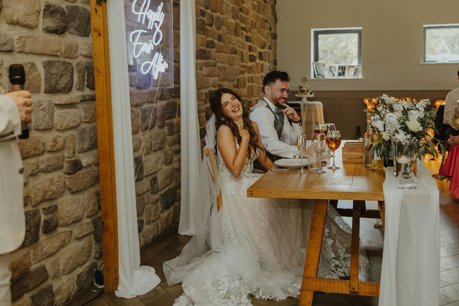 Wedding celebration in a charming stone-walled venue with wooden tables.