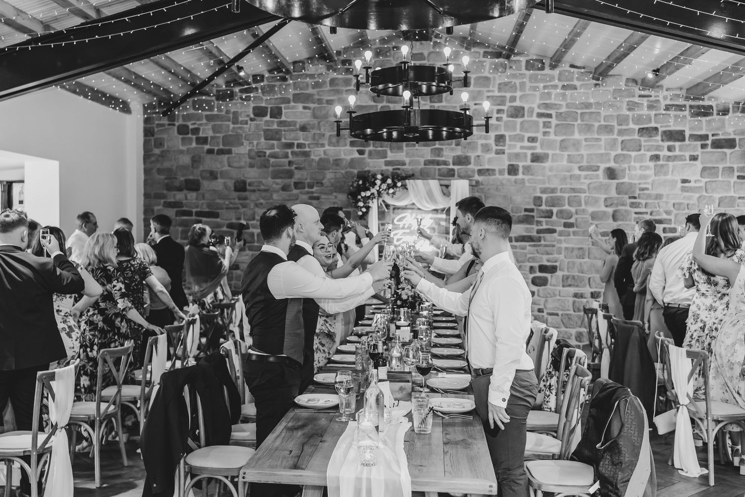 Black and white photo of wedding guests celebrating in industrial venue.