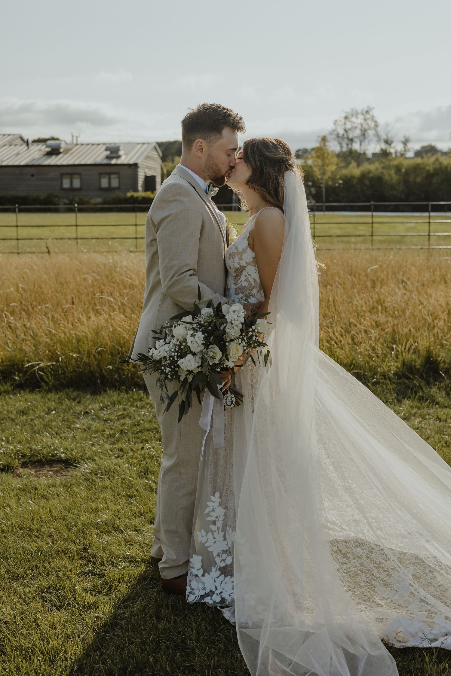 Intimate moment between newlyweds with stunning floral bouquet in rustic setting.