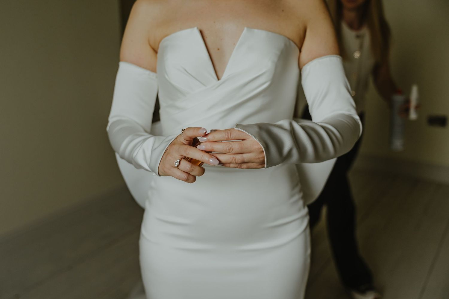 Detail shot of white wedding dress with long sleeves and fitted bodice.