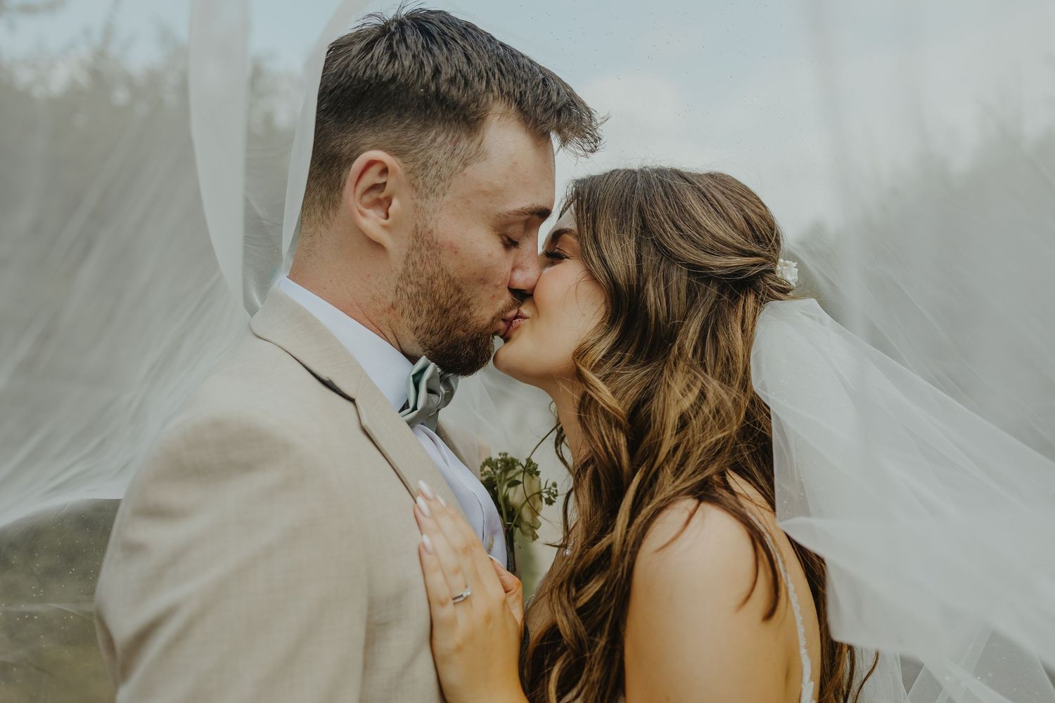 Romantic wedding couple shares an intimate kiss against a soft, dreamy backdrop.