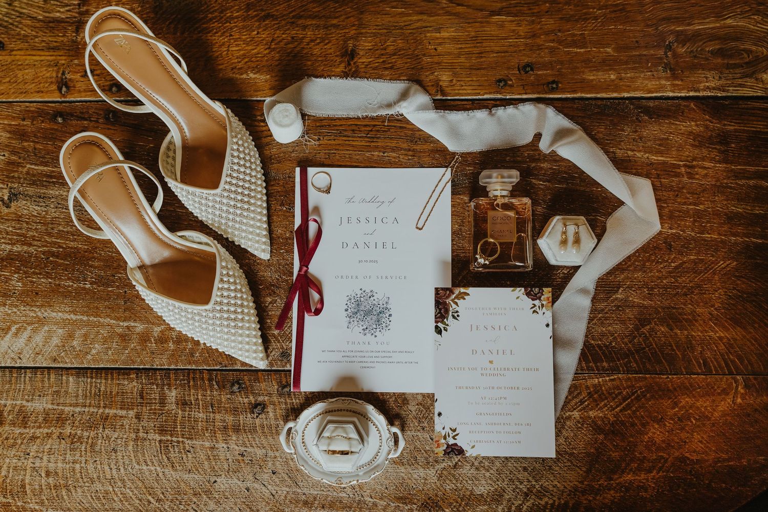 Wedding details flatlay with invitations, perfume, and white mesh bridal shoes.