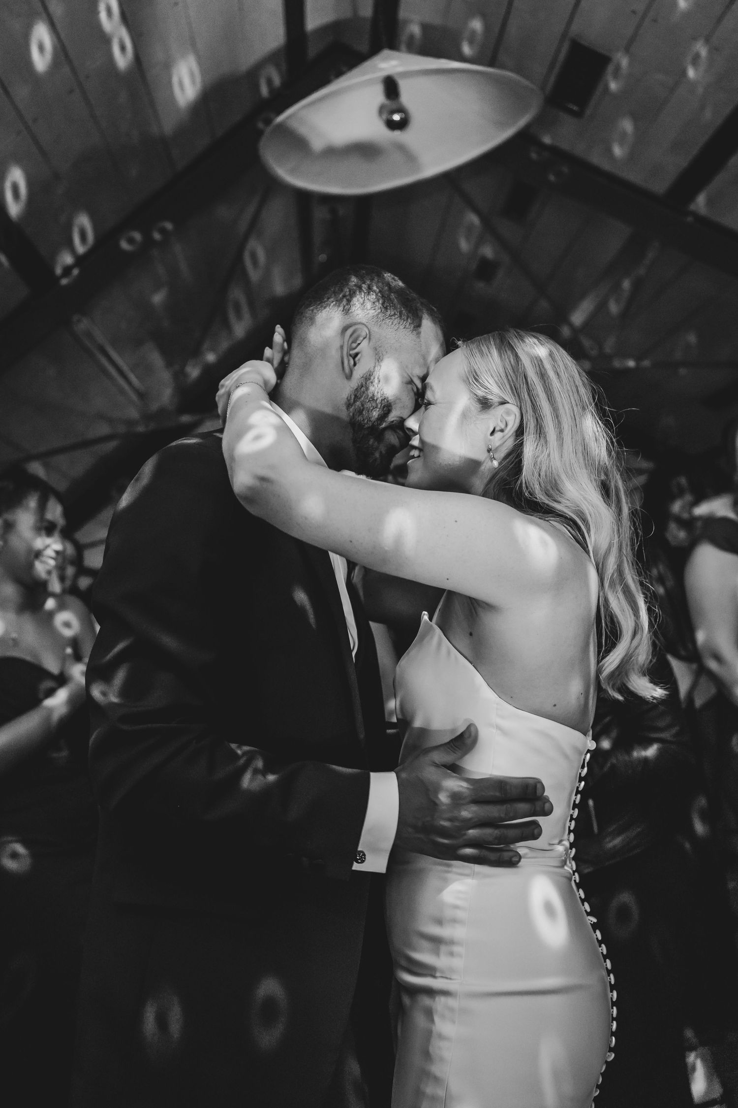 Wedding couple shares a romantic dance moment under moody lighting at their reception celebration.