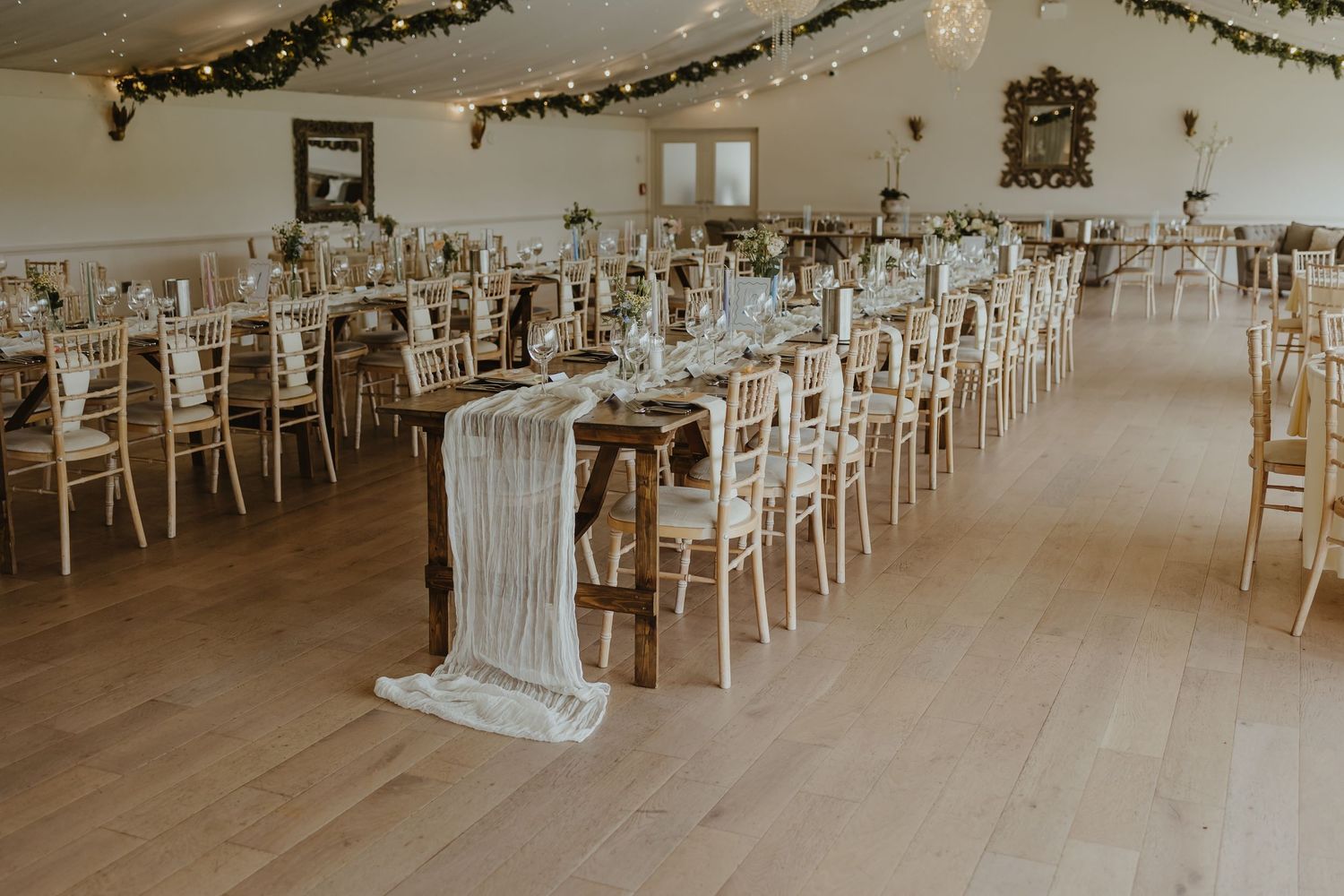 Elegant wedding reception venue with white chairs and decorative garland.