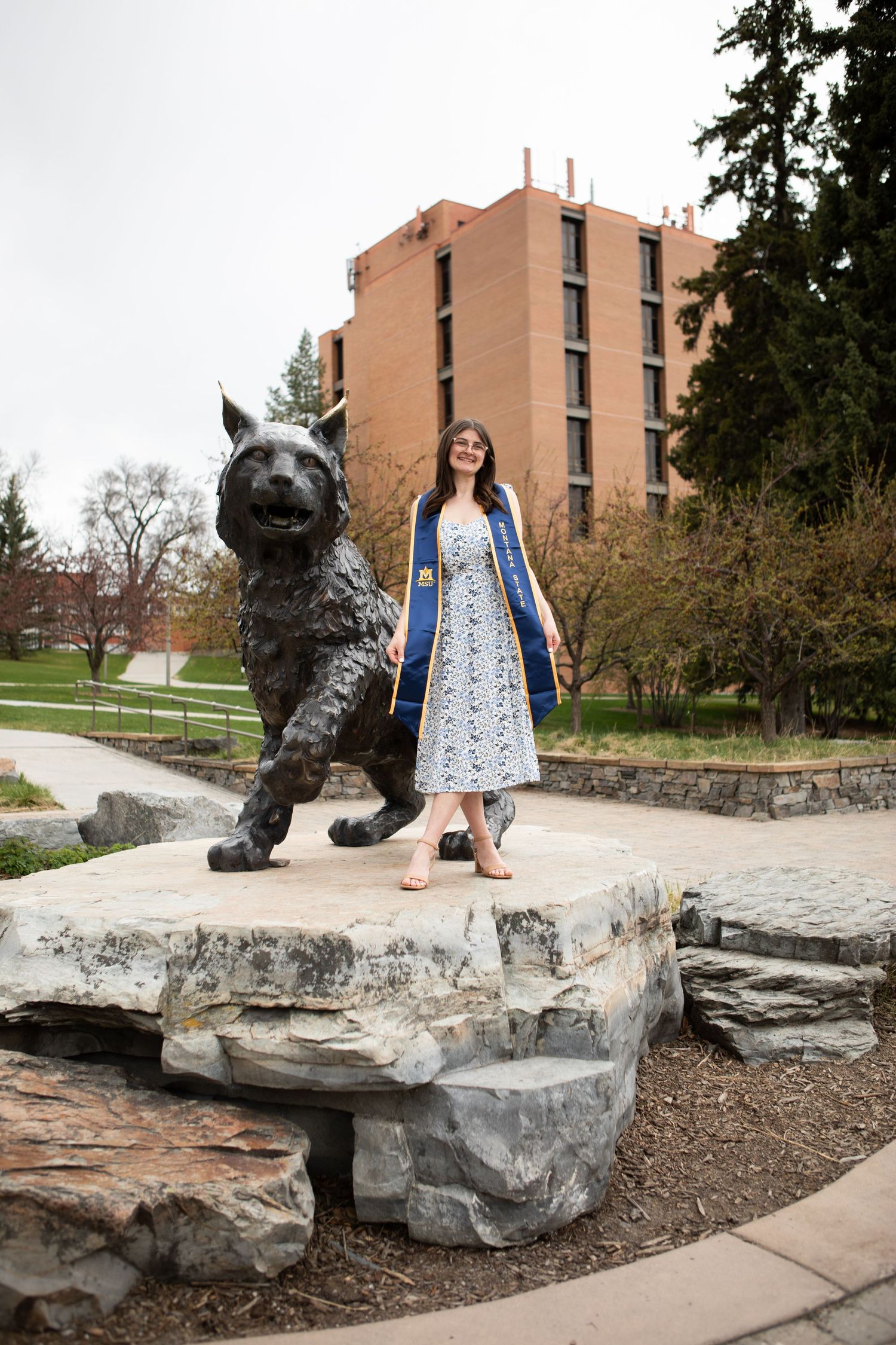 A Montana State grad stands by Spirit the Bobcat on campus in Bozeman, Montana.