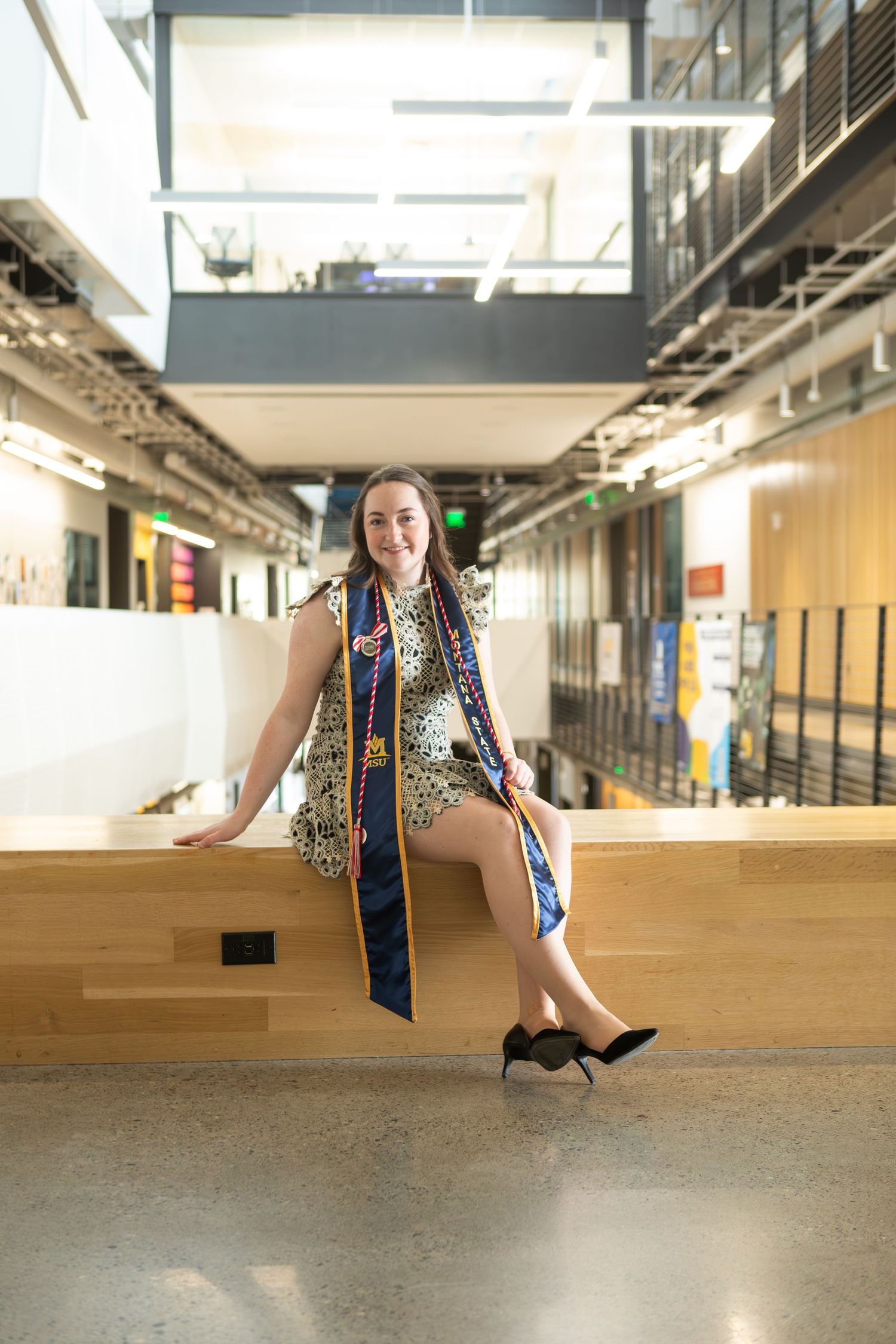 A Montana State University  Grad sits at the top of the steps in Norm Asbjornson Hall in Bozeman, MT.
