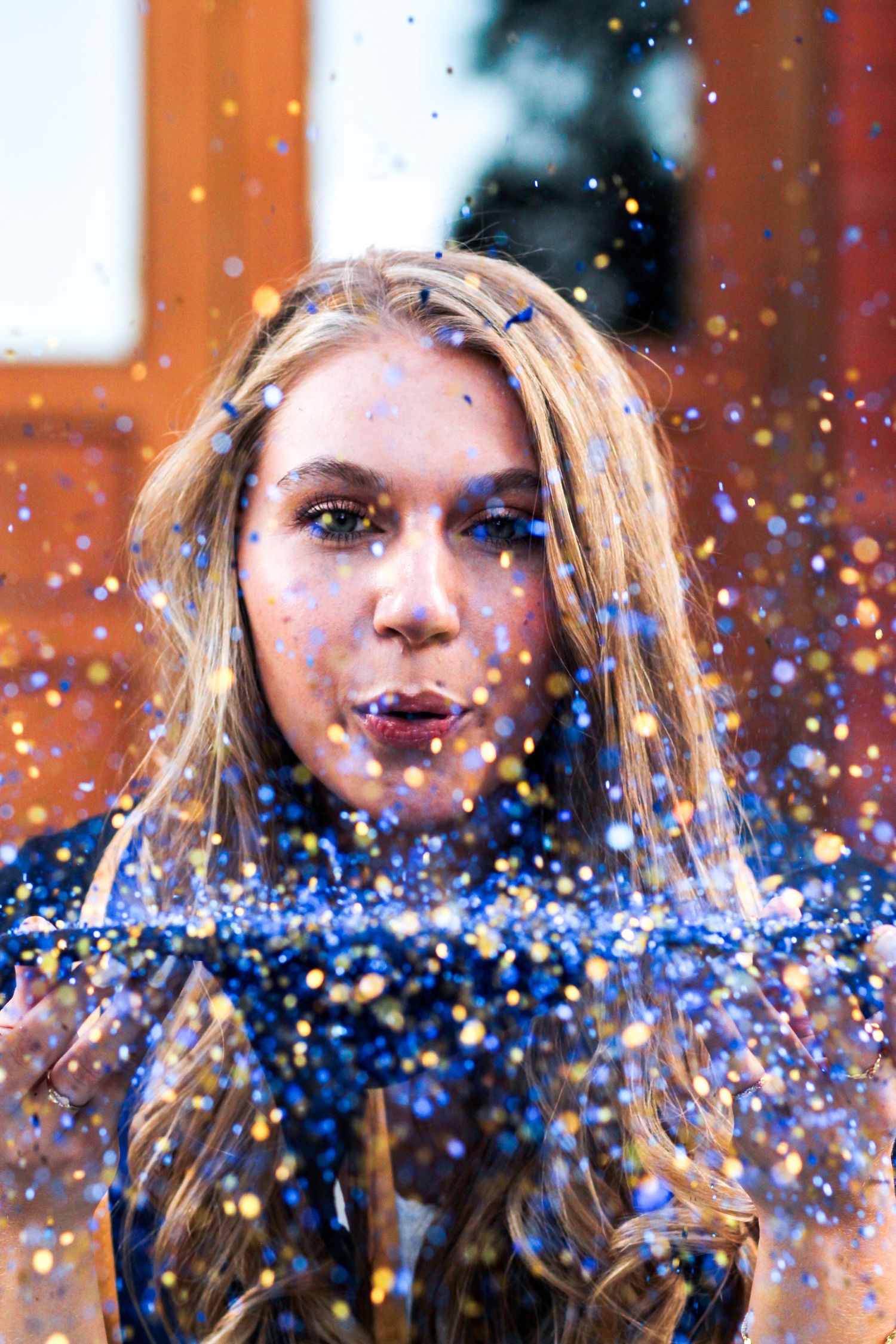 A Montana State University Grad blowing off blue and gold glitter from her cap.