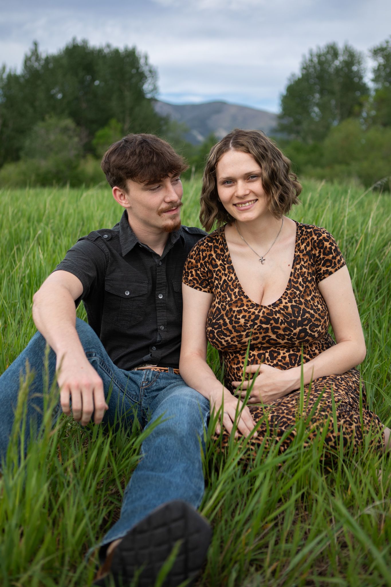 A Bozeman Montana couple sits in a field for a maternity session.