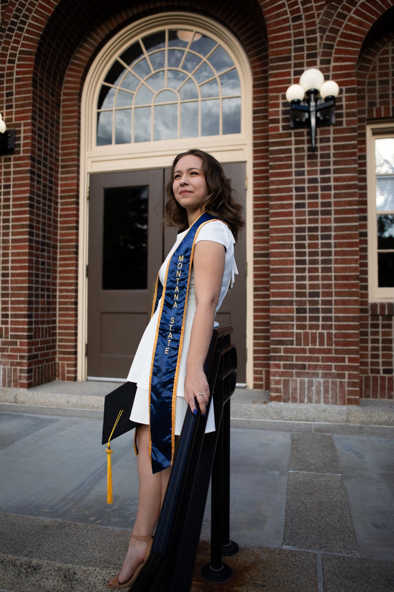 A Montana State University grad stands in front of Herrick Hall on campus in Bozeman, Montana.