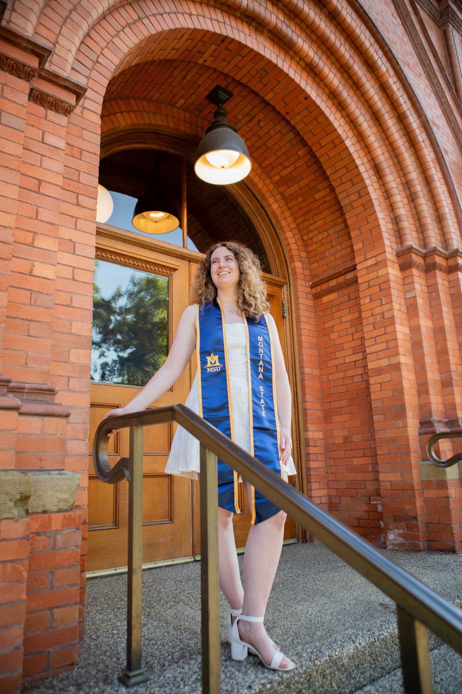 A Montana State University grad stands on the steps of Montana Hall in Bozeman.
