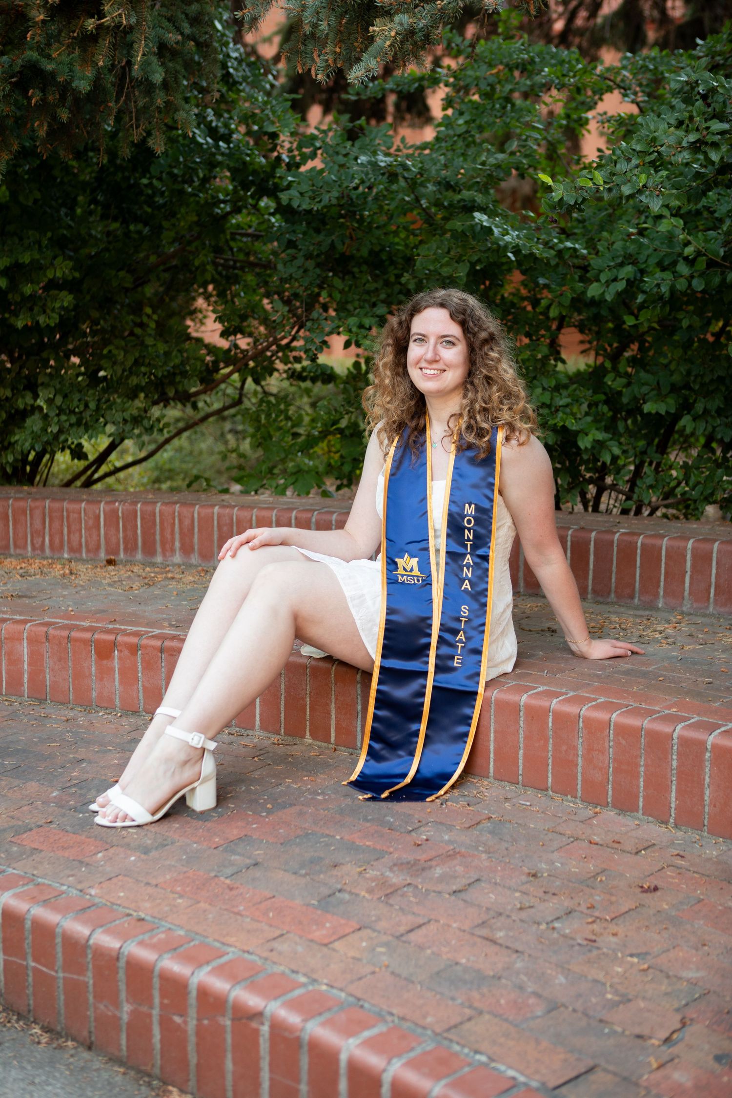 A Montana State University grad sits on steps in the Wilson Hall courtyard in Bozeman.