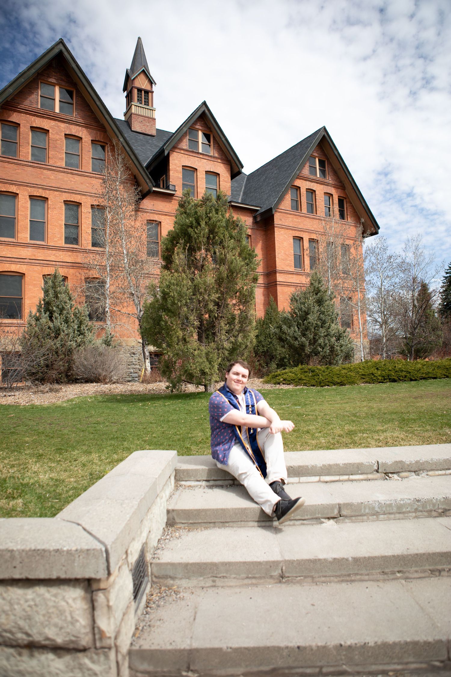 A Montana State grad sit on the steps in front of Montana Hall on campus in Bozeman.