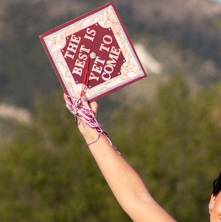 Detail image of a Montana Senior holding her decorate graduation cap in the air