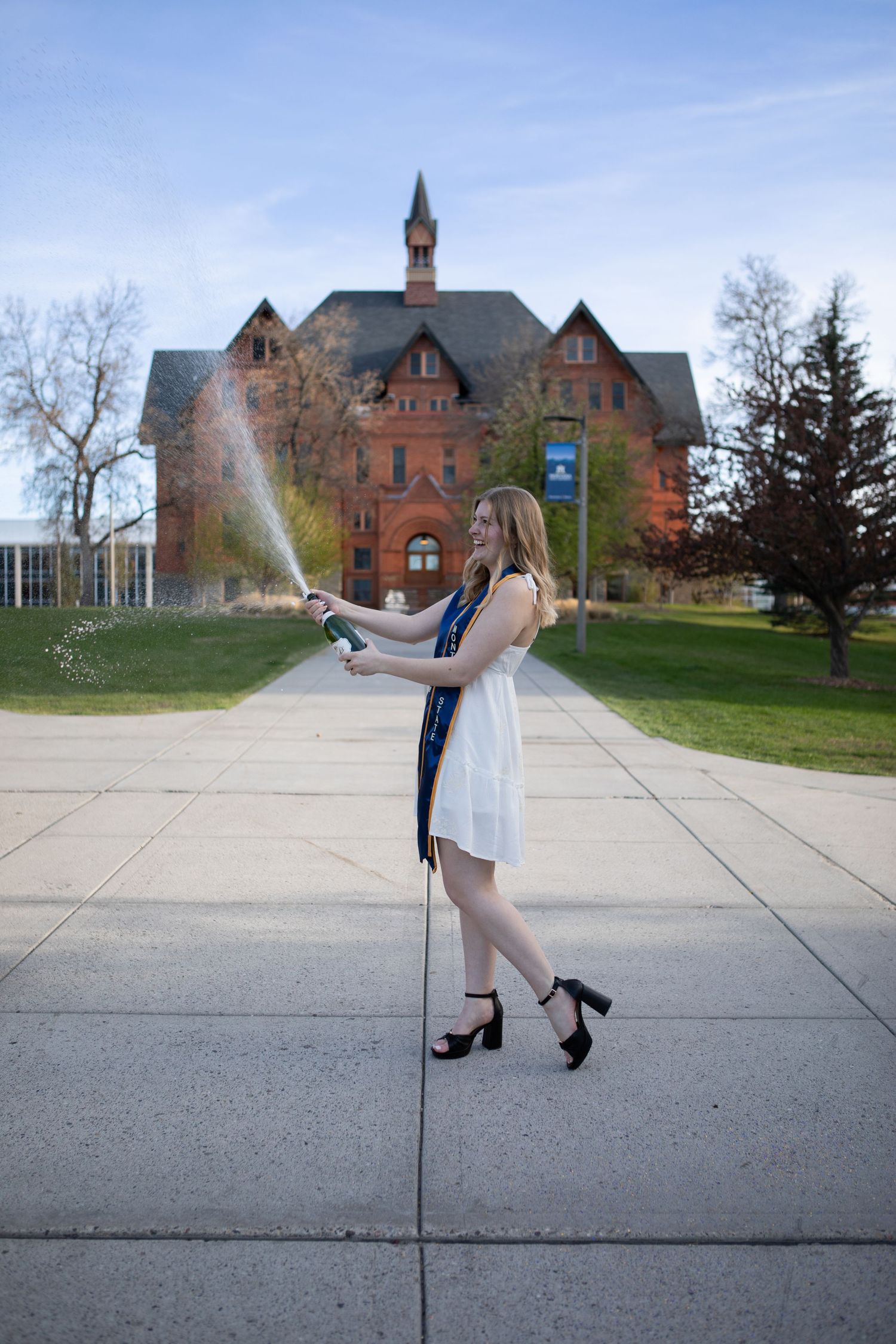 A Montana State University Grad sprays a bottle of champagne in front of Montana Hall in Bozeman, Montana.