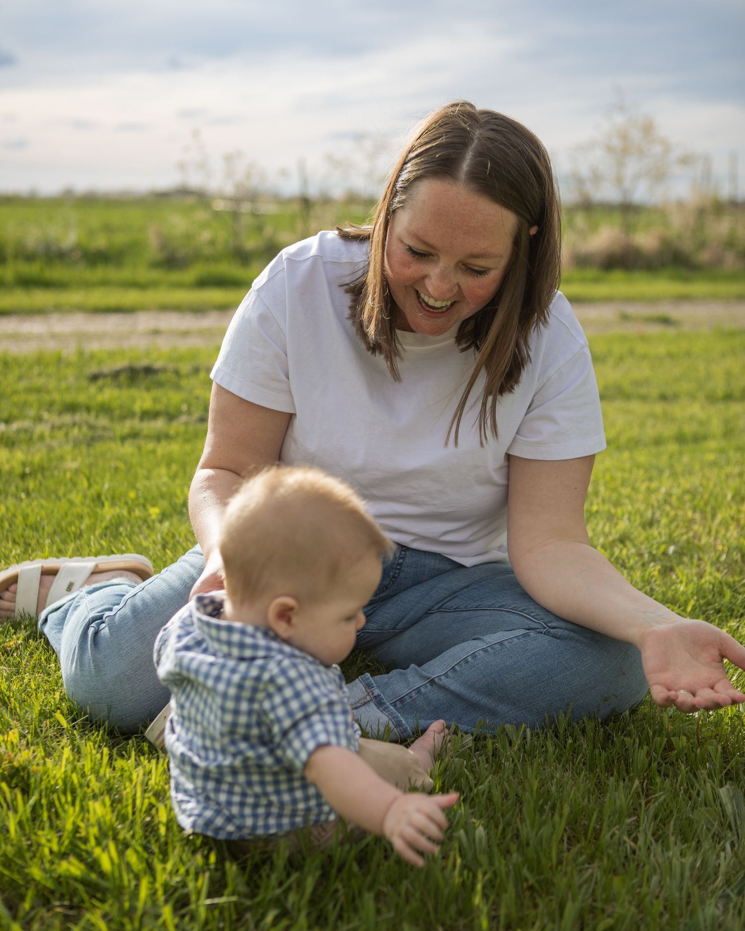 A Bozeman mom playing with her baby in a field.