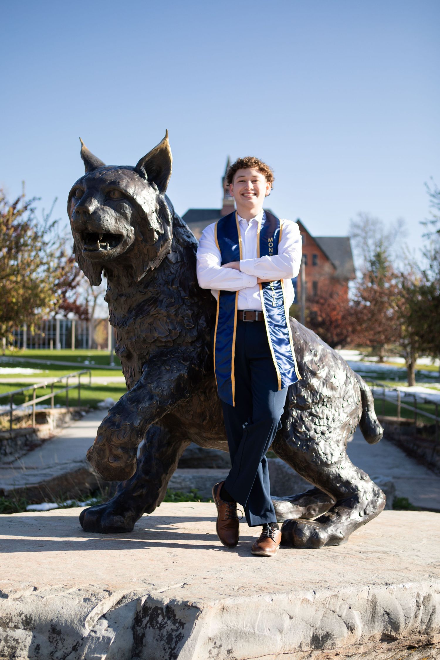 A Montana State University Grad leans against Spirit the Bobcat in Bozeman, Montana.